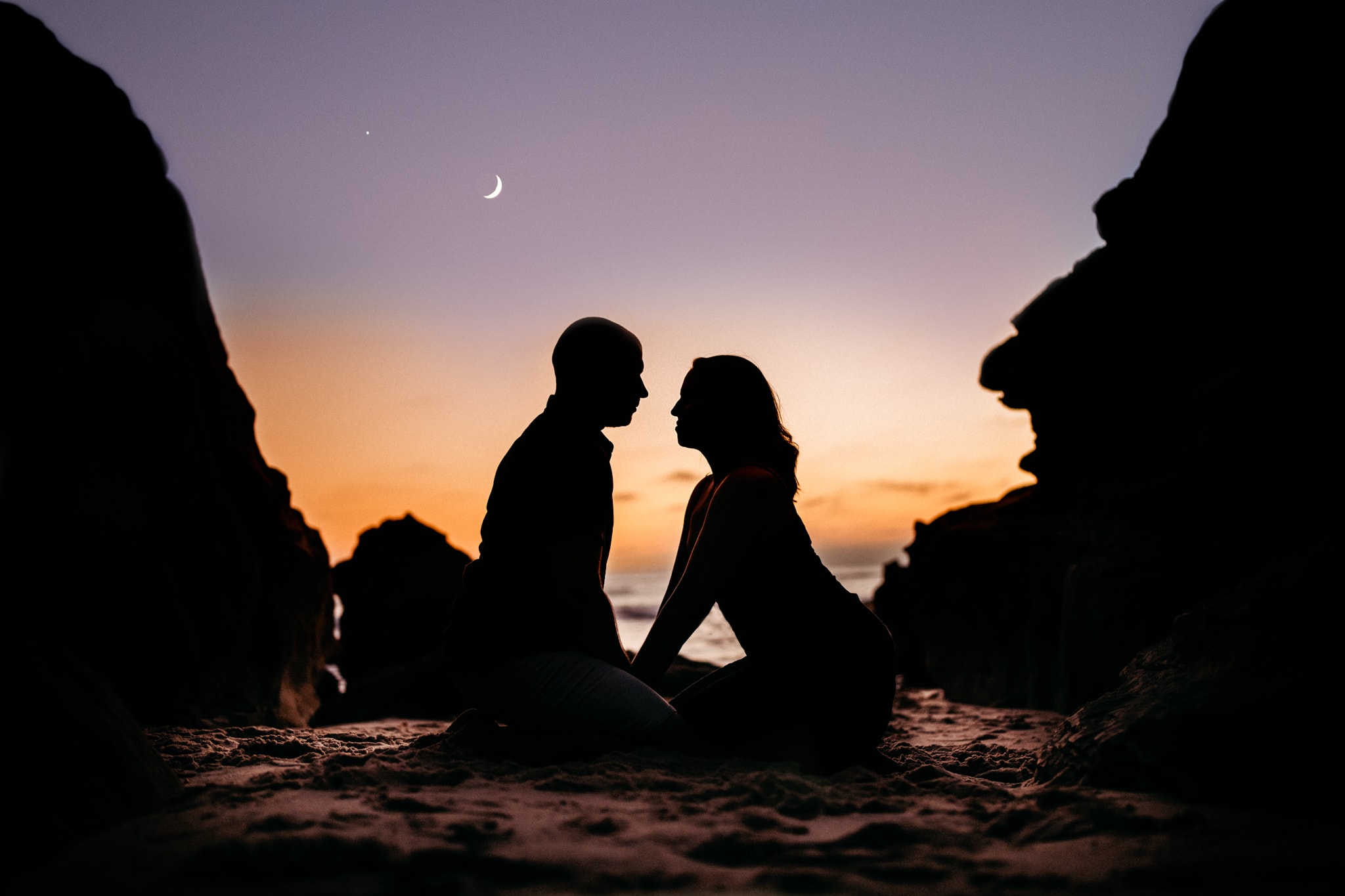 Couple posing together in intimate embrace in San Diego's Windansea Beach