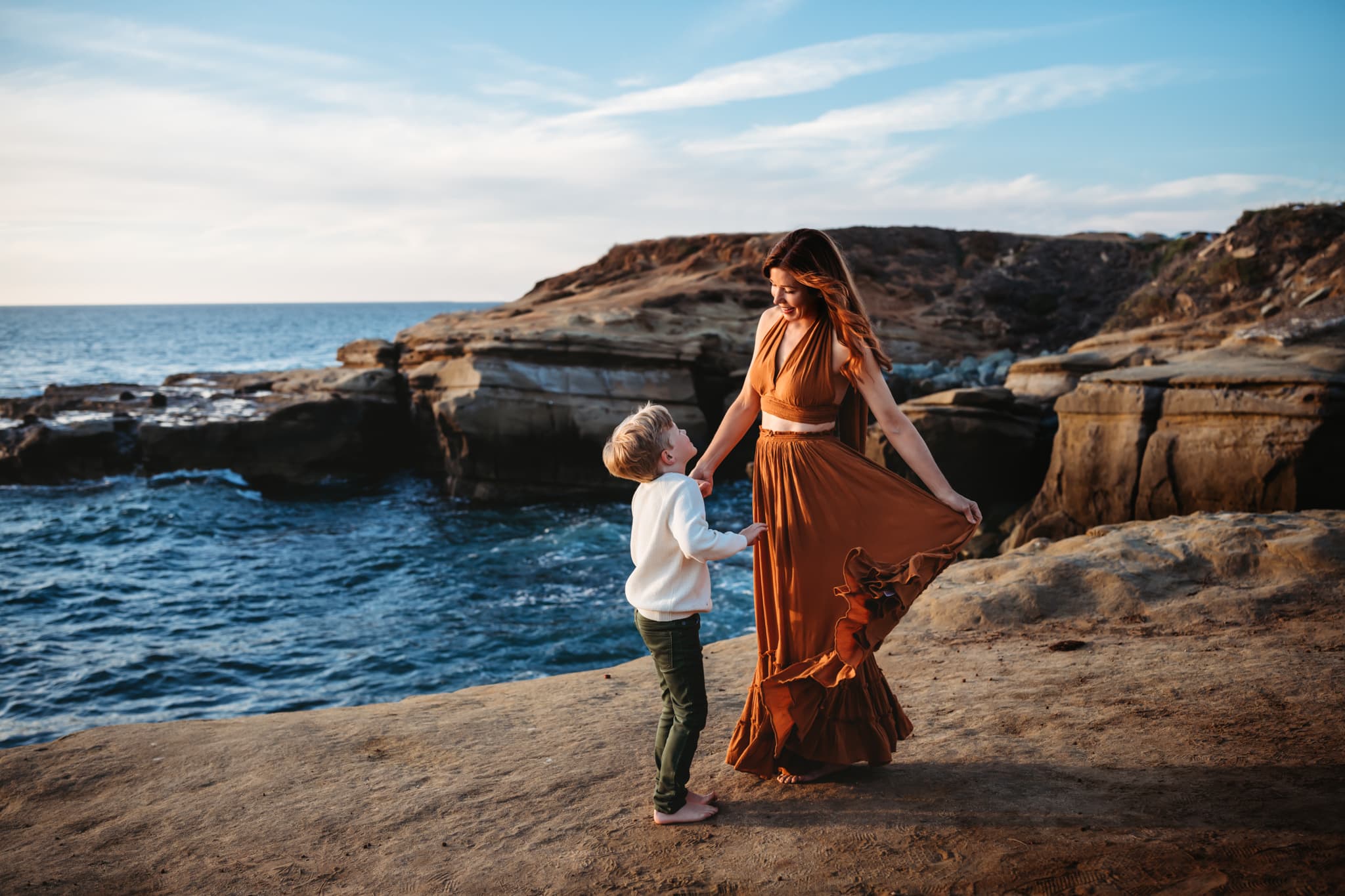 Mother wearing Free People dress dancing with her son at Sunset Cliffs in San Diego