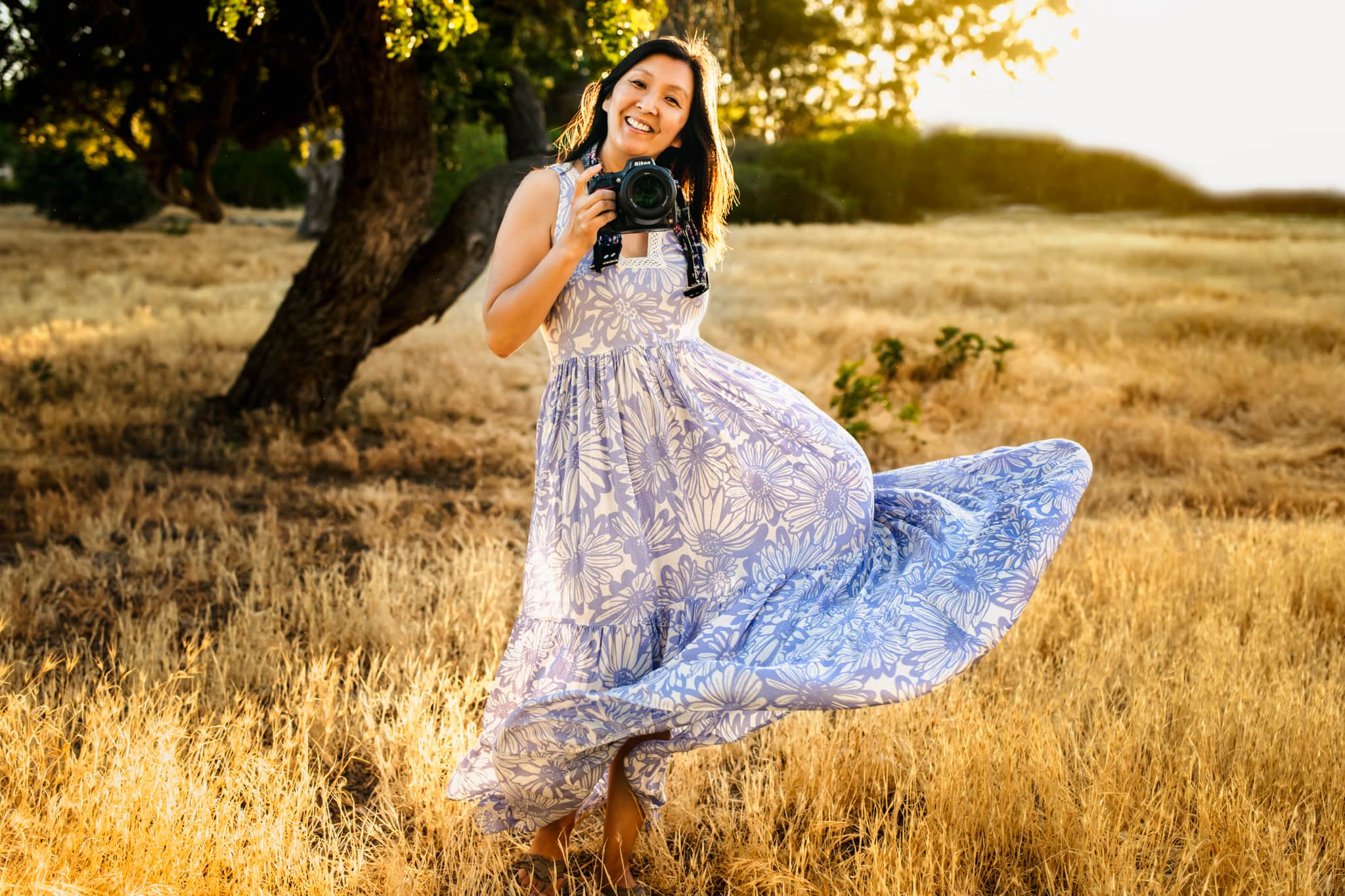 Kim Belverud in a golden field wearing Free People dress while holding camera