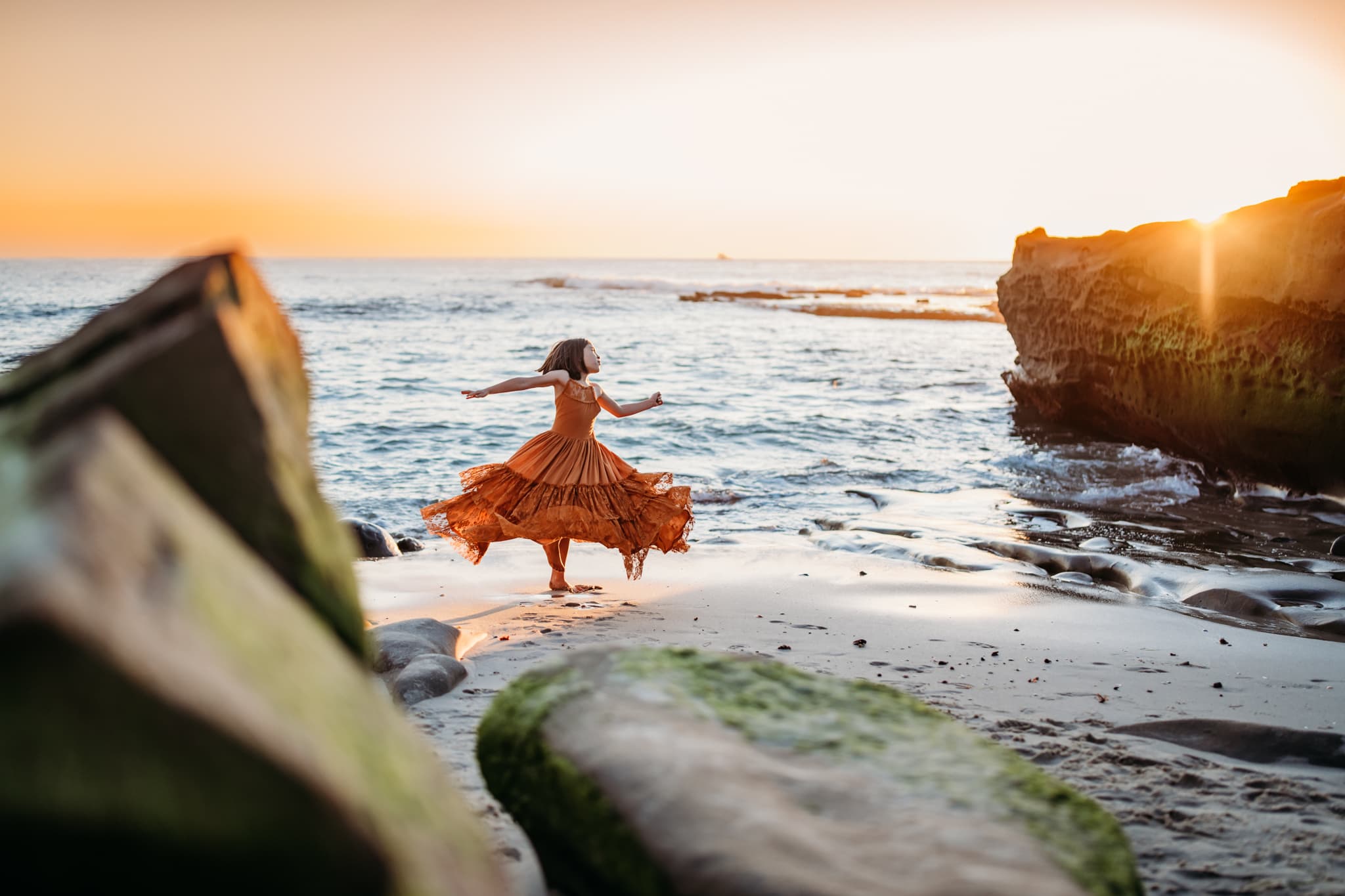 Girl twirling on beach in Joyfolie dress at Windansea Beach