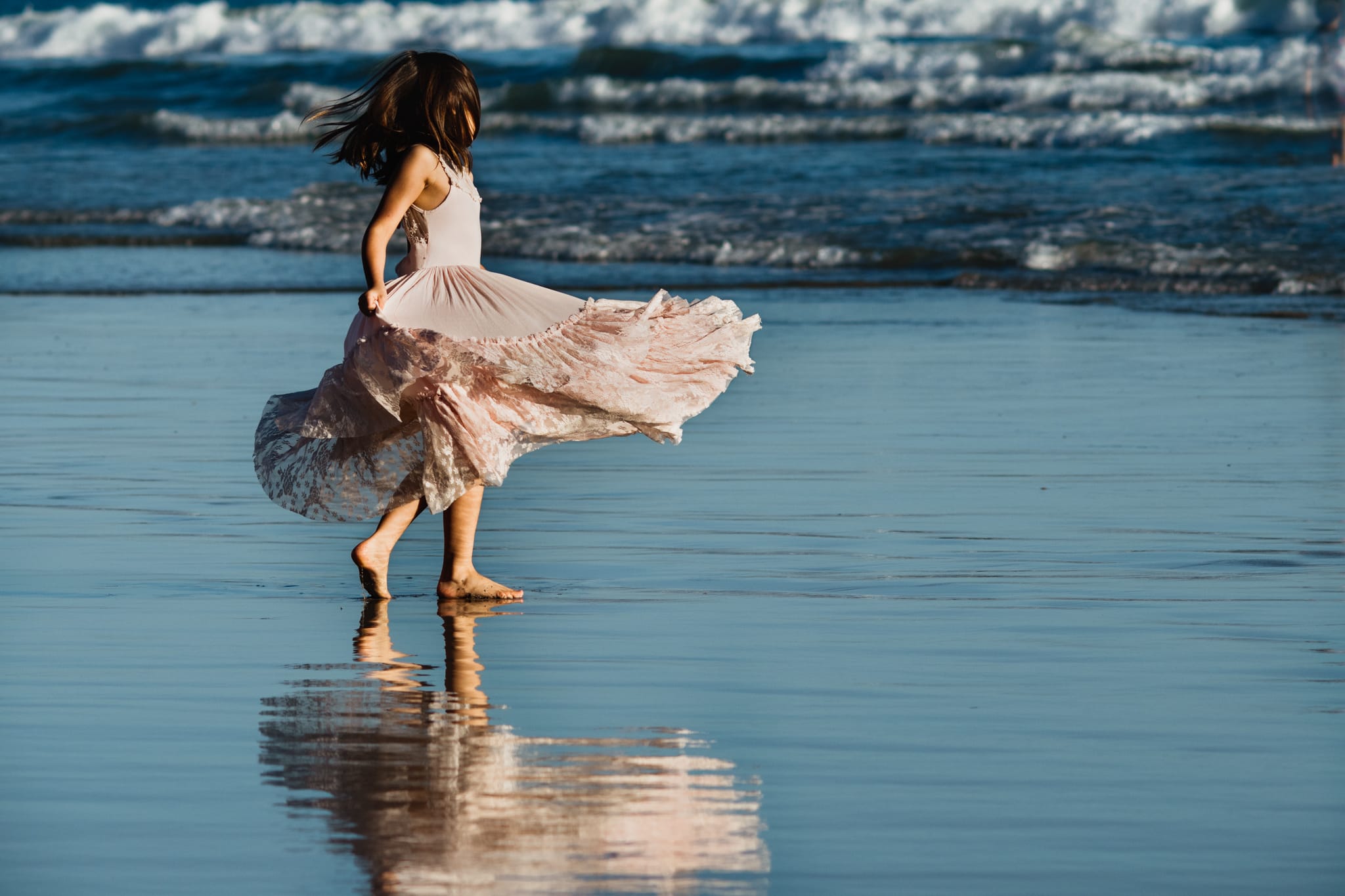 Girl twirling on beach in Joyfolie dress at Coronado Beach