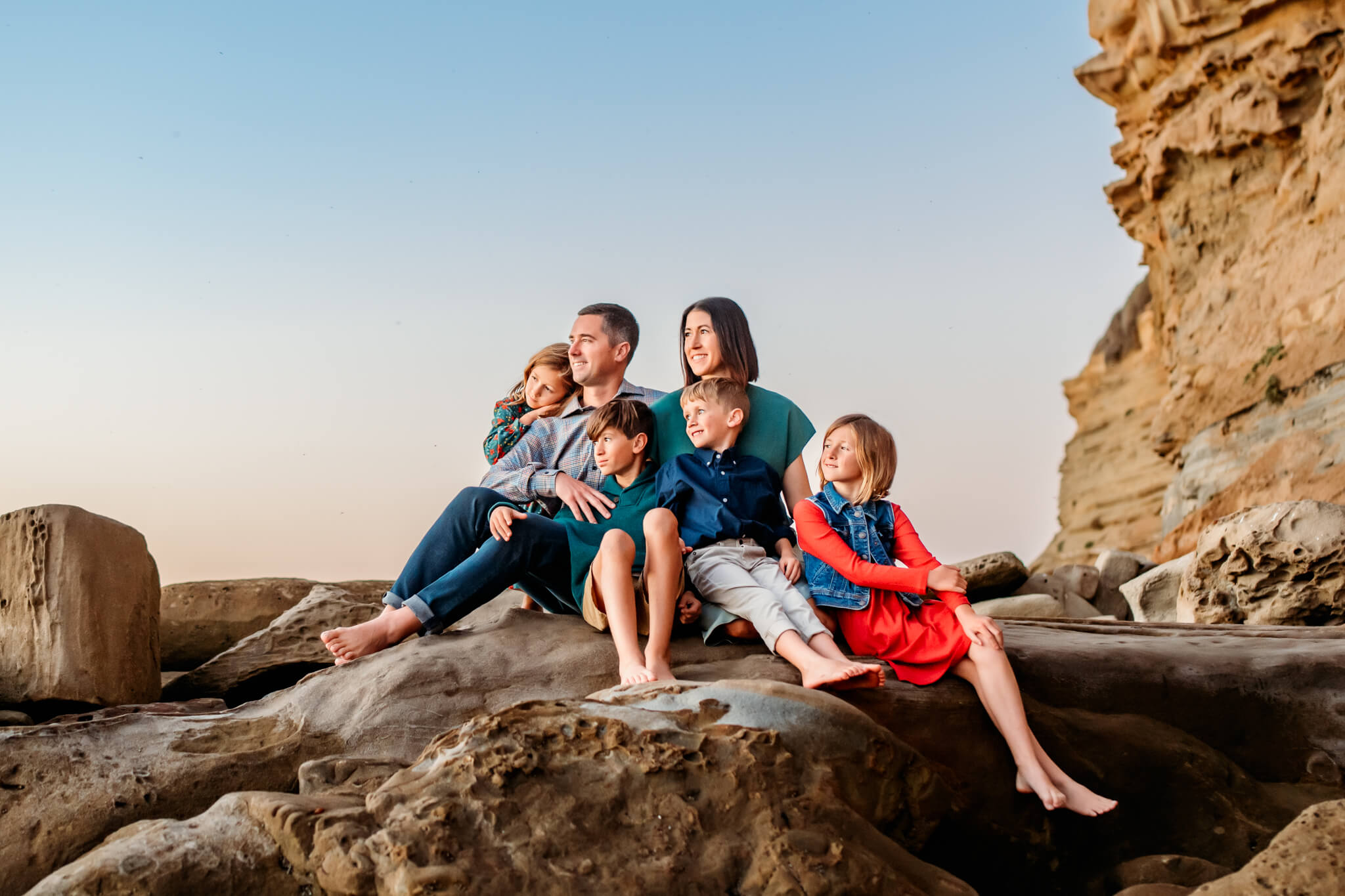 San Diego Family of 6 at Sunset Cliffs sitting on a cliff and looking out at the Pacific Ocean
